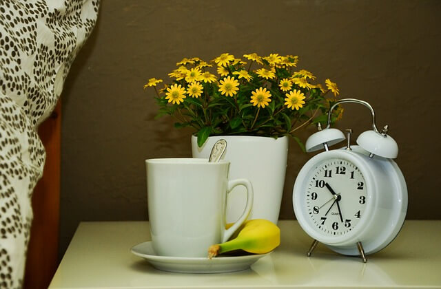 テーブルの上にコップと花と時計